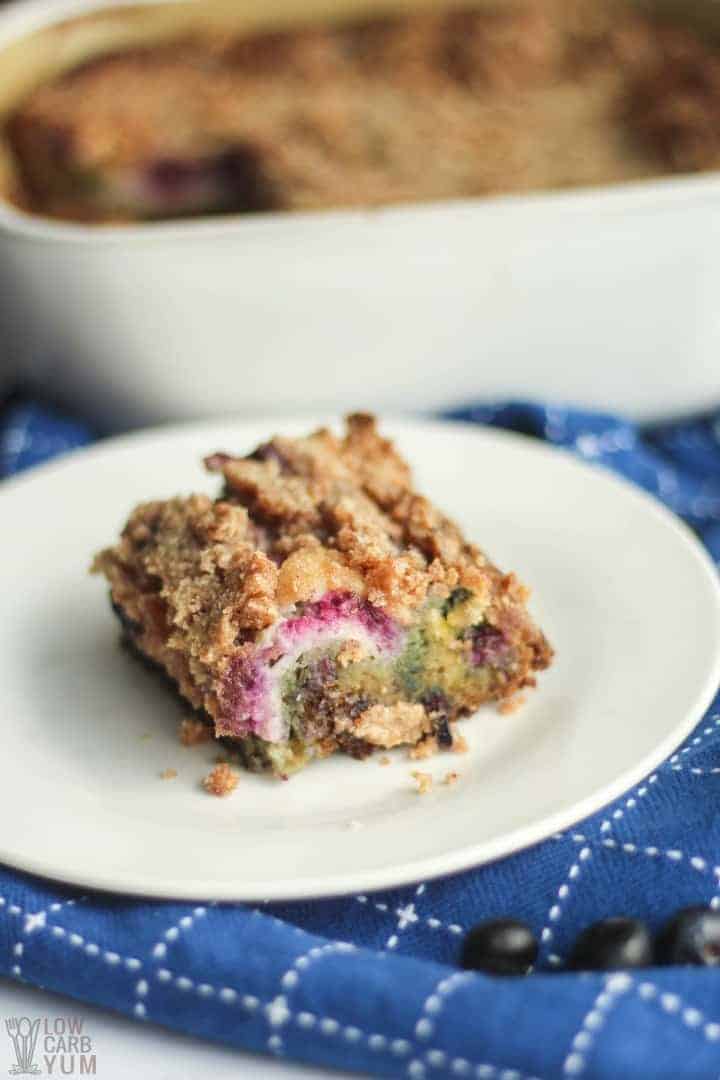 slice of moist blueberry keto coffee cake on a white plate