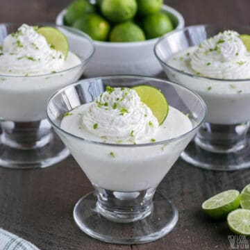 key lime mousse in glass dessert dishes with whipped cream and lime