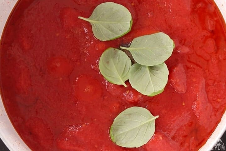 adding seasoning and basil leaves