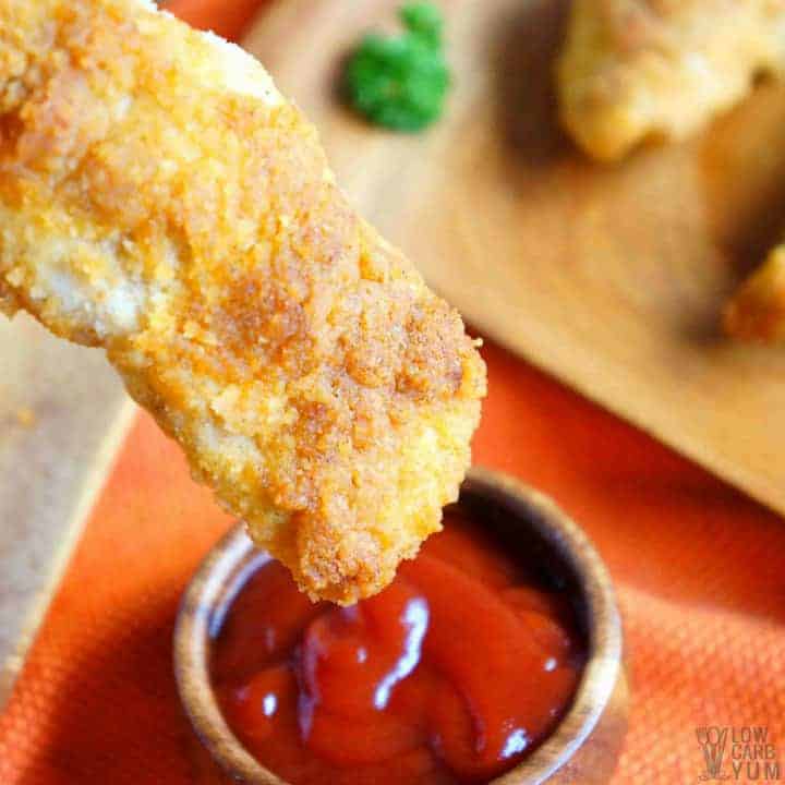 Dipping keto paleo coconut flour chicken tenders in ketchup 