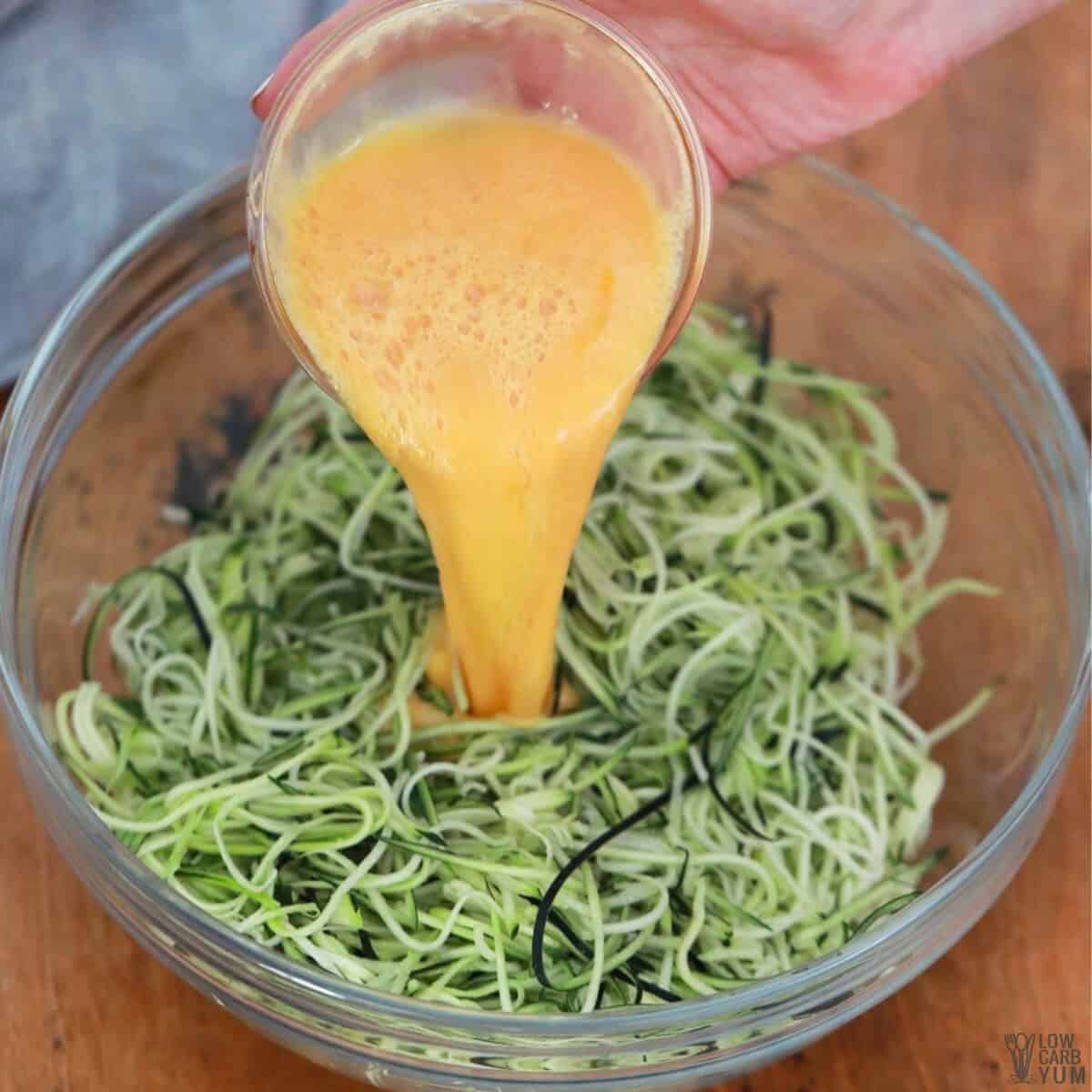 adding beaten egg to spiralized zucchini noodles