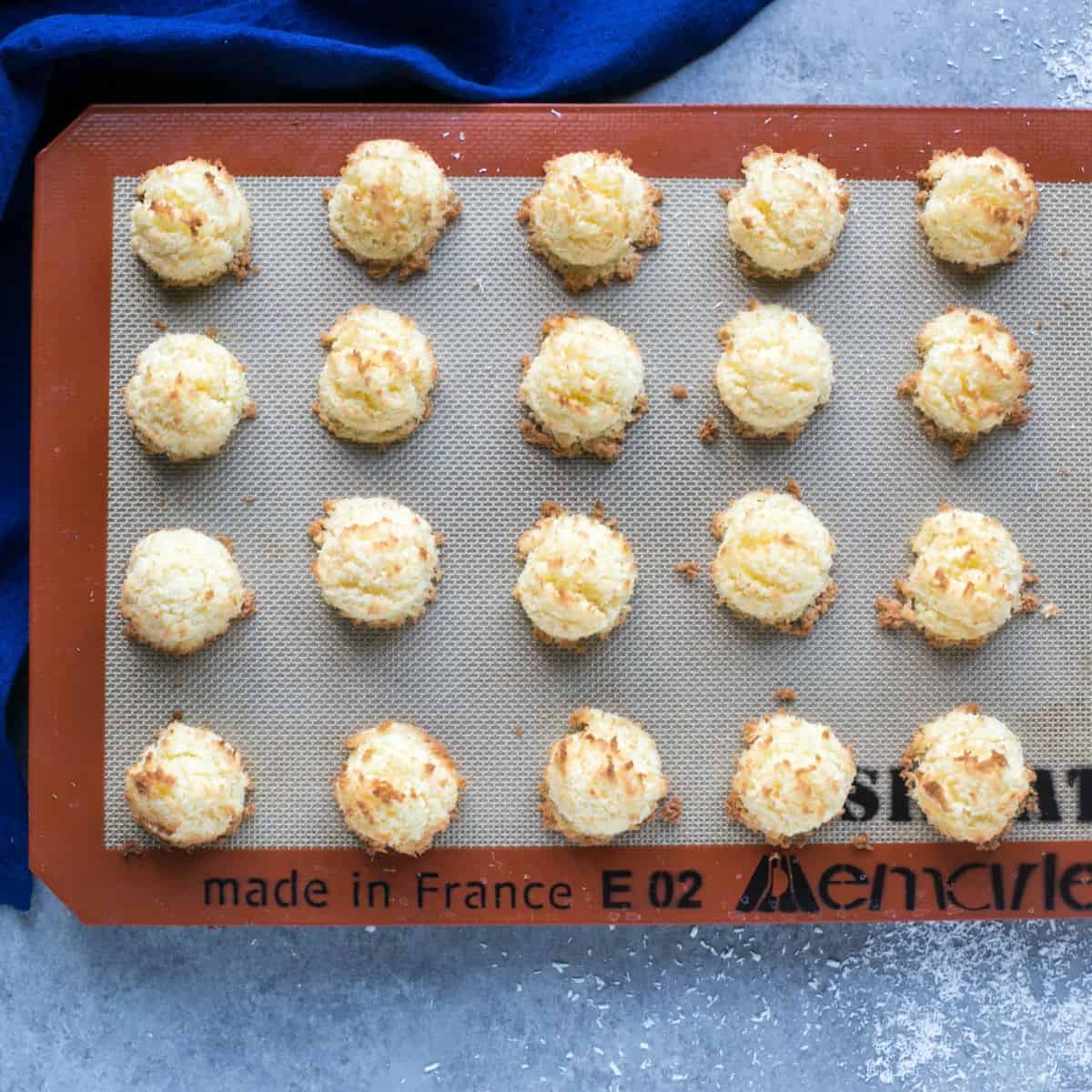 baked coconut macaroons on silicone mat lined cookie sheet.