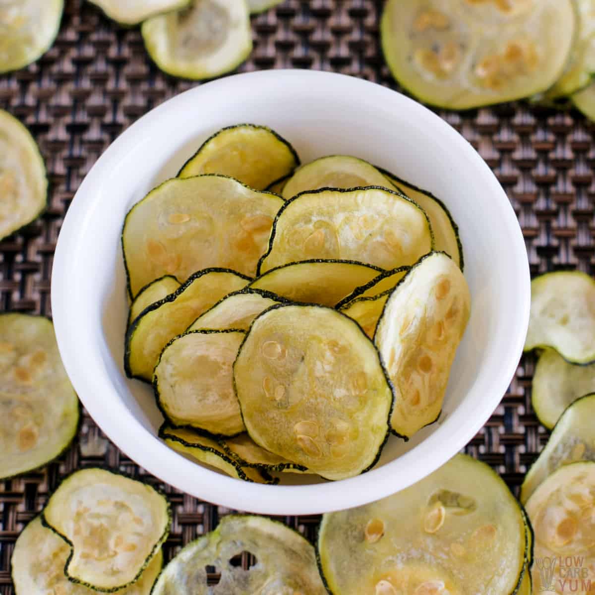 zucchini chips in white bowl and on brown placemat.