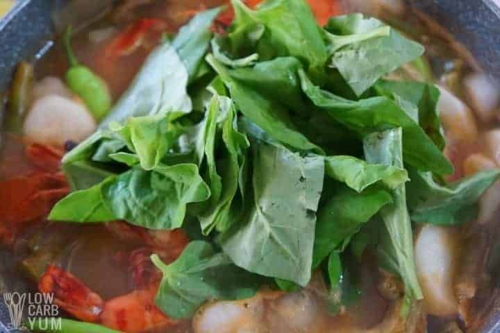 Adding spinach to the Filipino soup