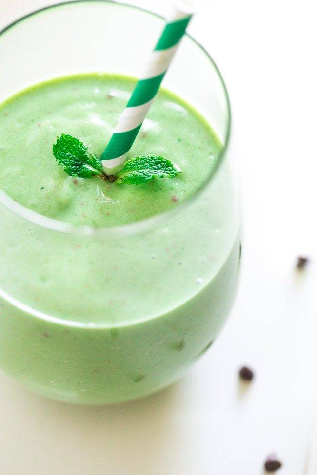 chocolate mint green smoothie in glass with green and white striped paper straw and sprig of mint