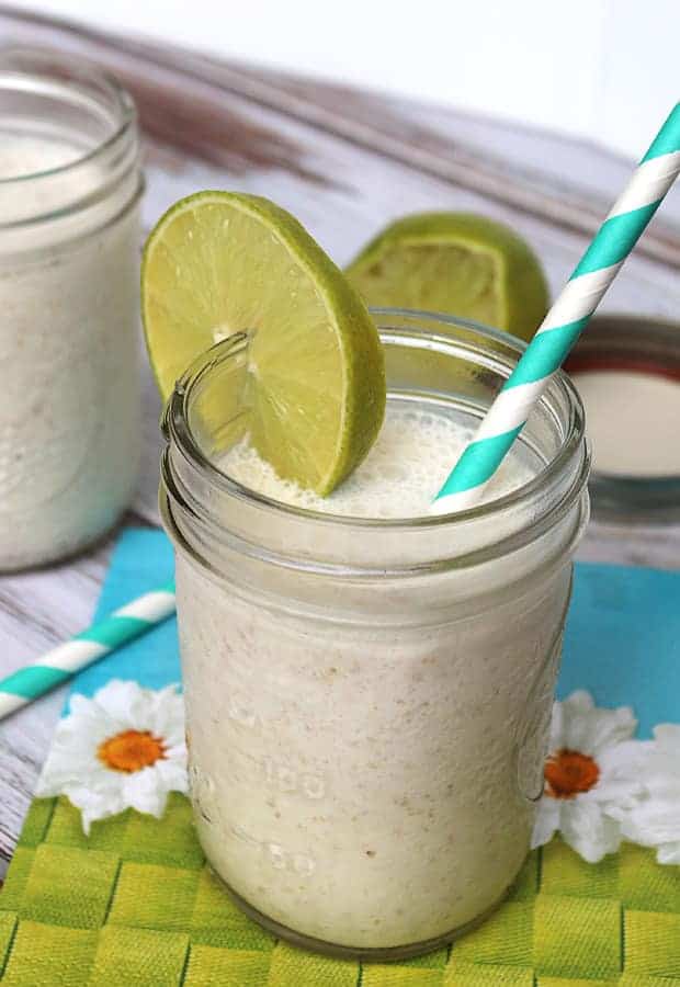 keto tropical smoothie in mason jar with slime slice on rim and straw in jar