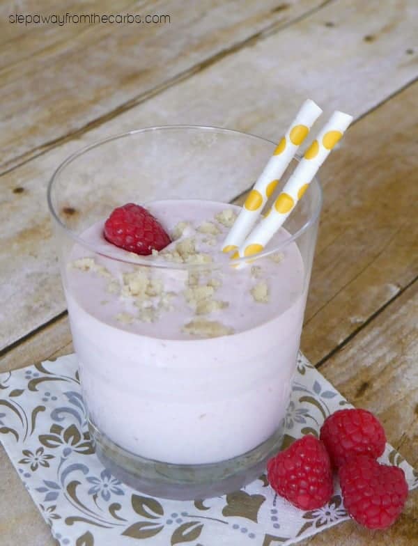 raspberry cheesecake smoothie in glass with 2 yellow polka dotted straws