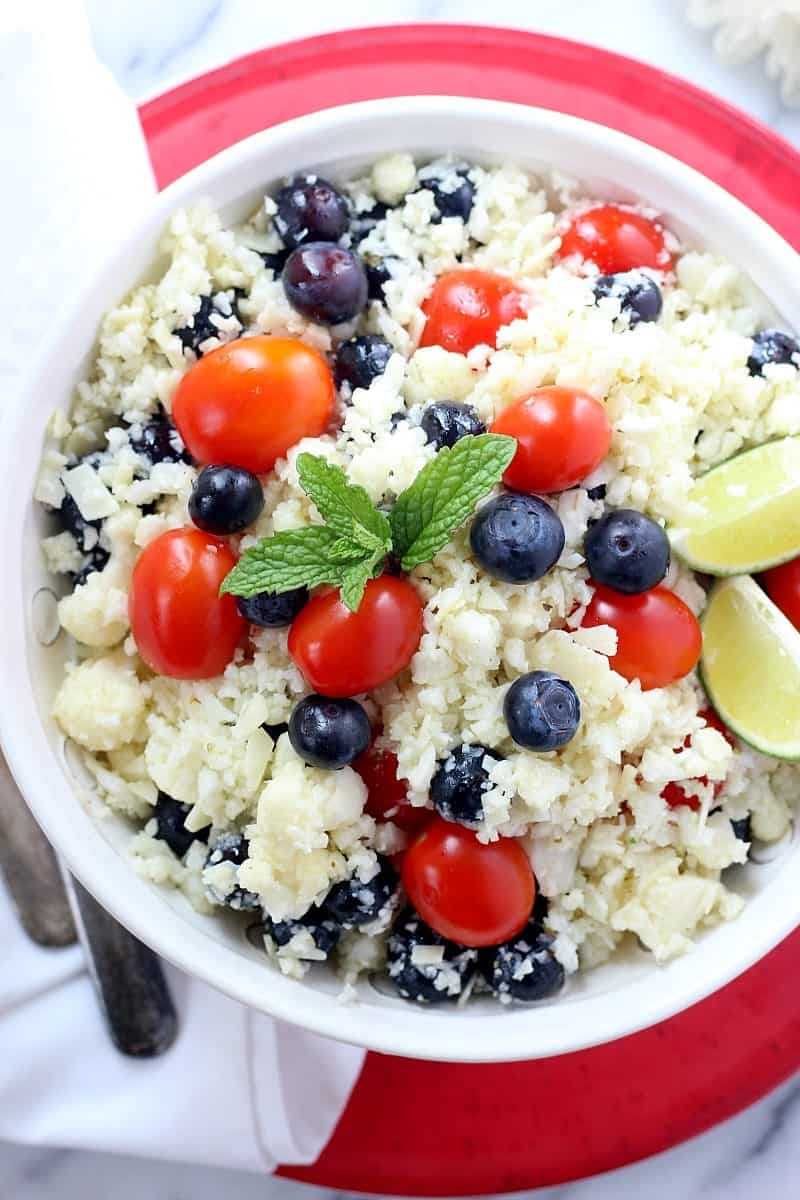 bowl of healthy Parmesan cauliflower rice salad with cherry tomatoes and fresh blueberries