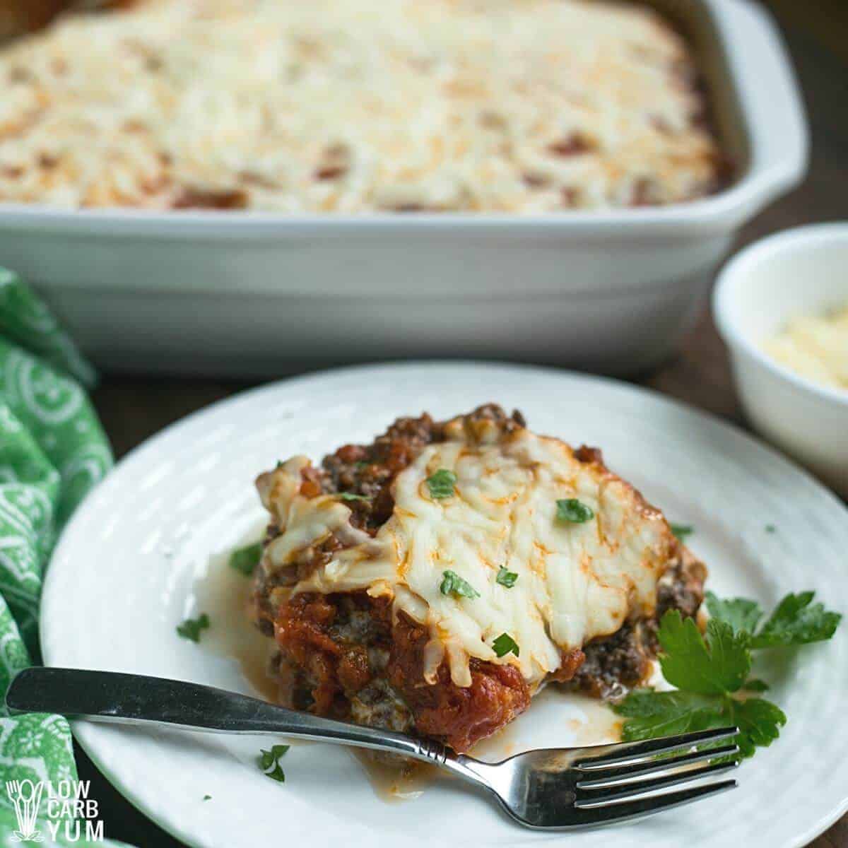 spaghetti squash lasagna slice on white plate with casserole dish