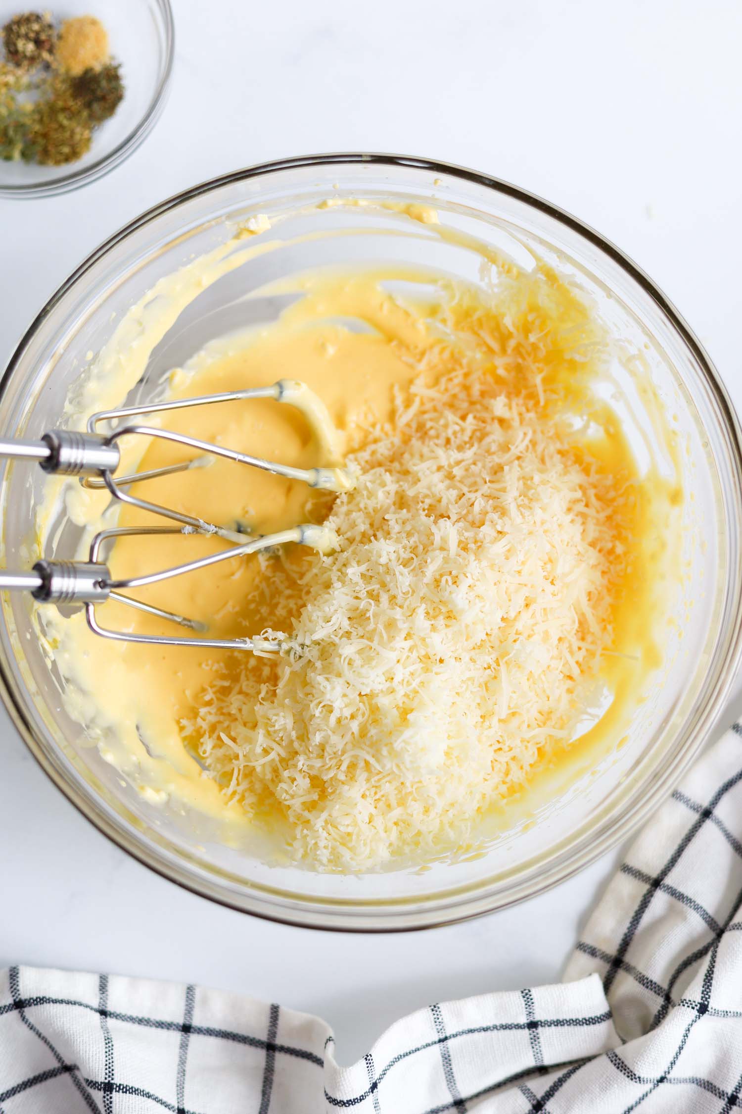 adding grated parmesan cheese to a bowl of pasta dough