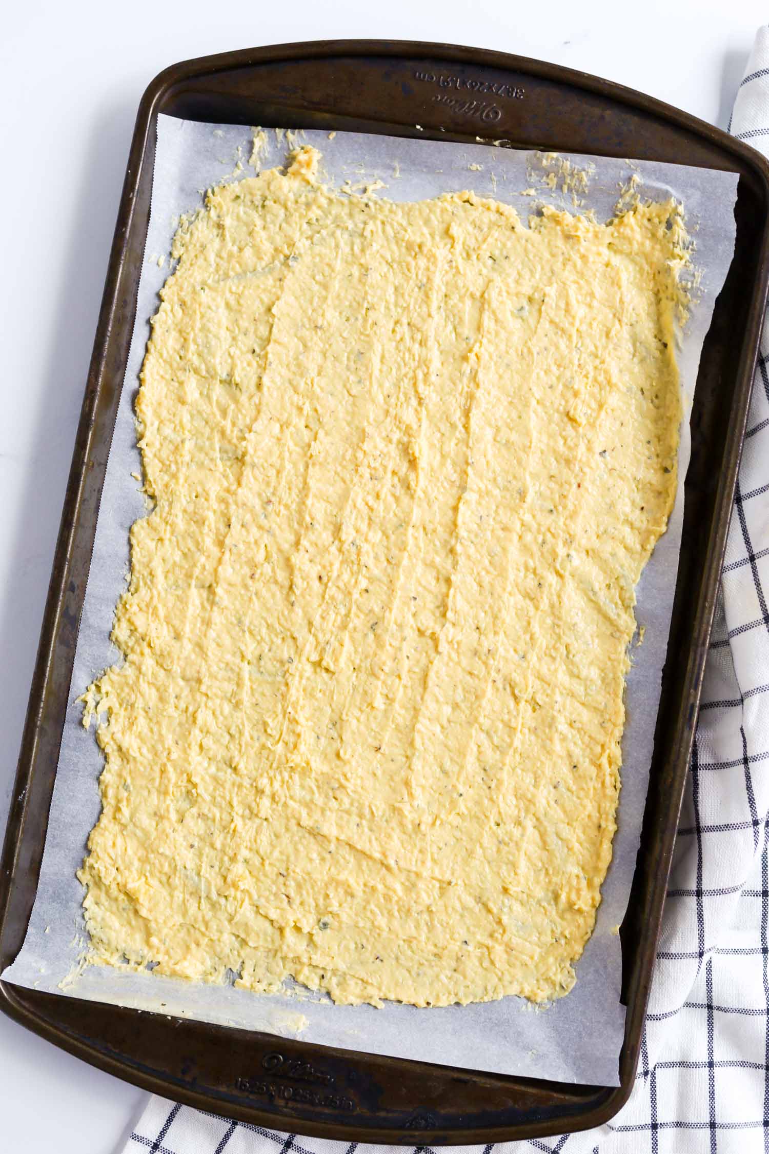 spreading out keto noodles dough onto parchment paper 