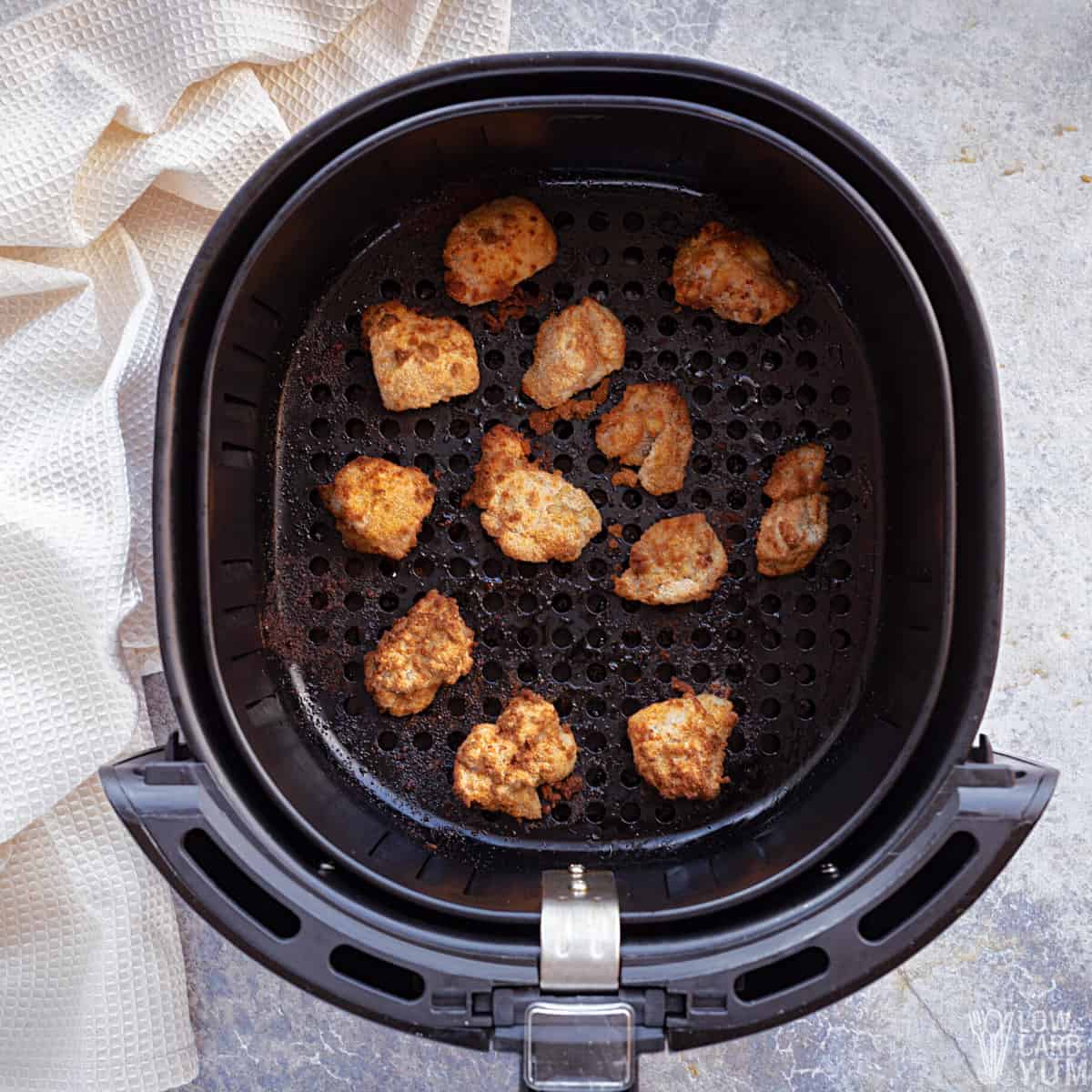 cooked chicken nuggets in air fryer basket.