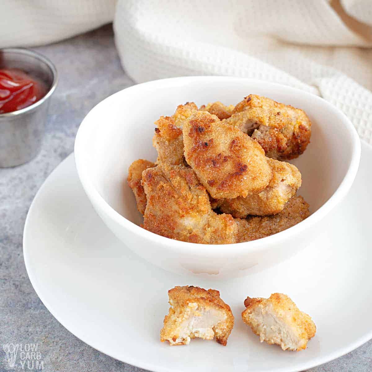 bowl of keto chicken nuggets with one sliced in half outside bowl.