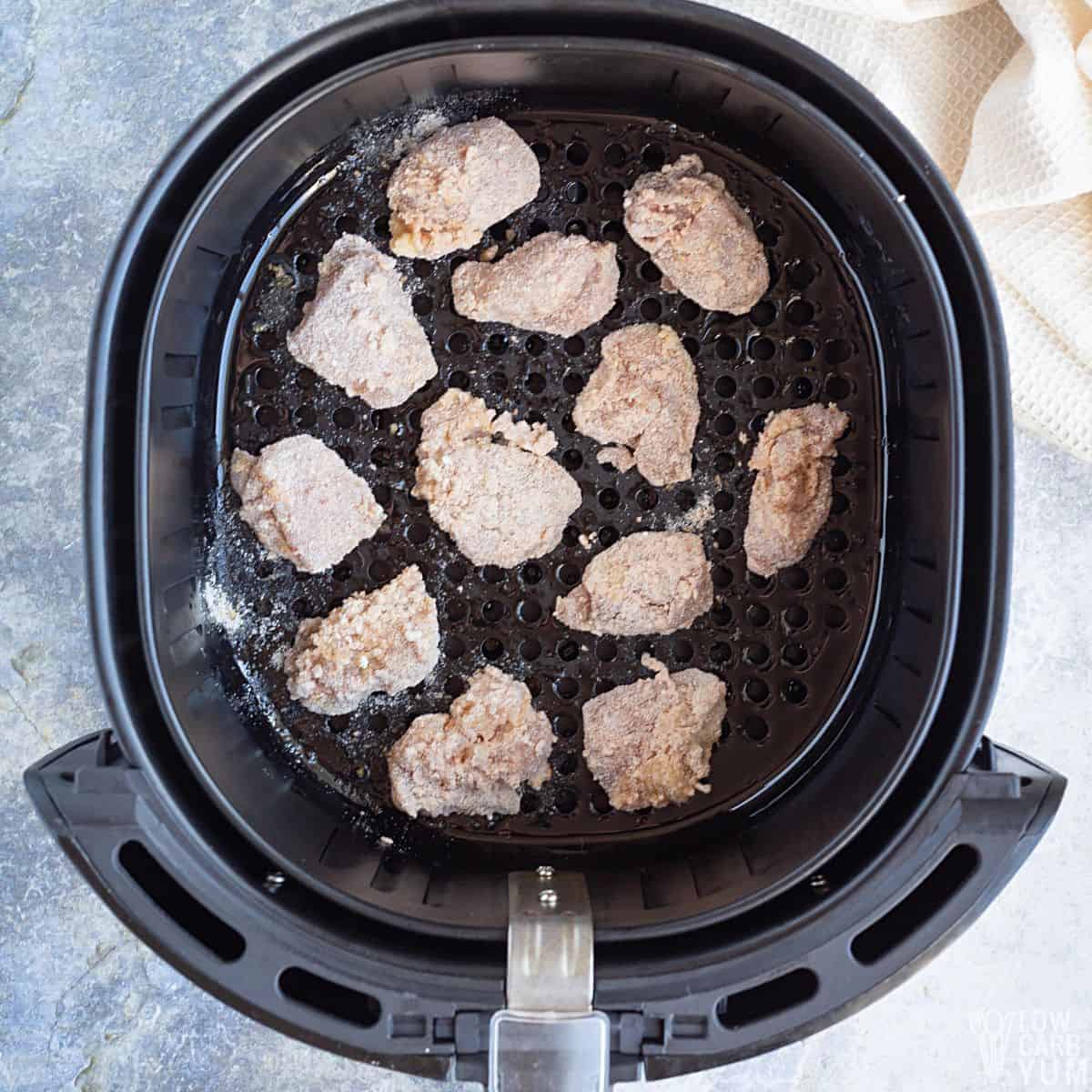 uncooked breaded keto chicken nuggets in air fryer basket.