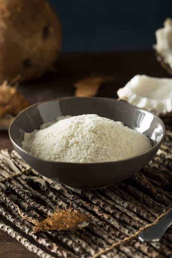 bowl of coconut flour with piece of coconut.