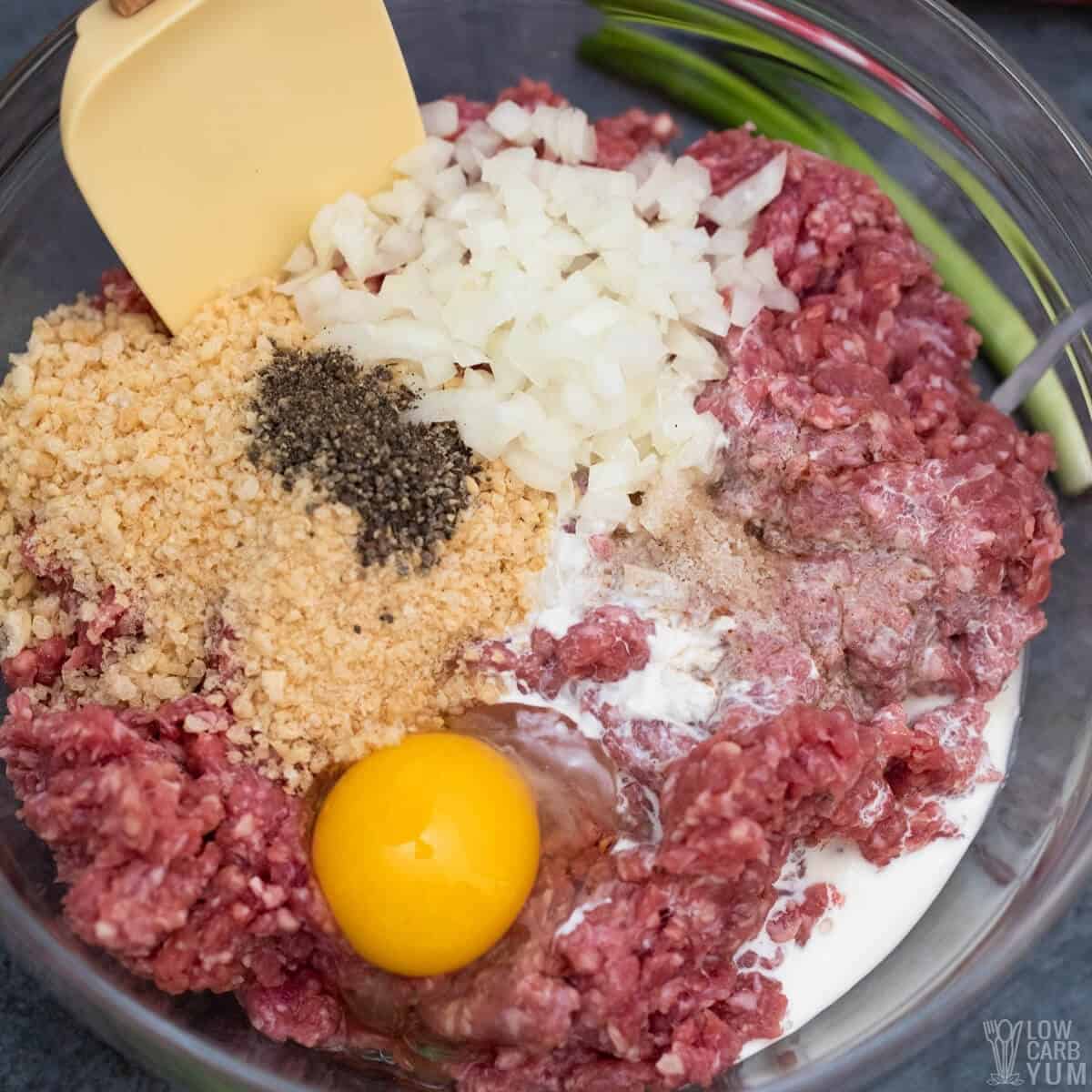 mixing all of the ingredients for japanese hamburger steaks in a large glass bowl