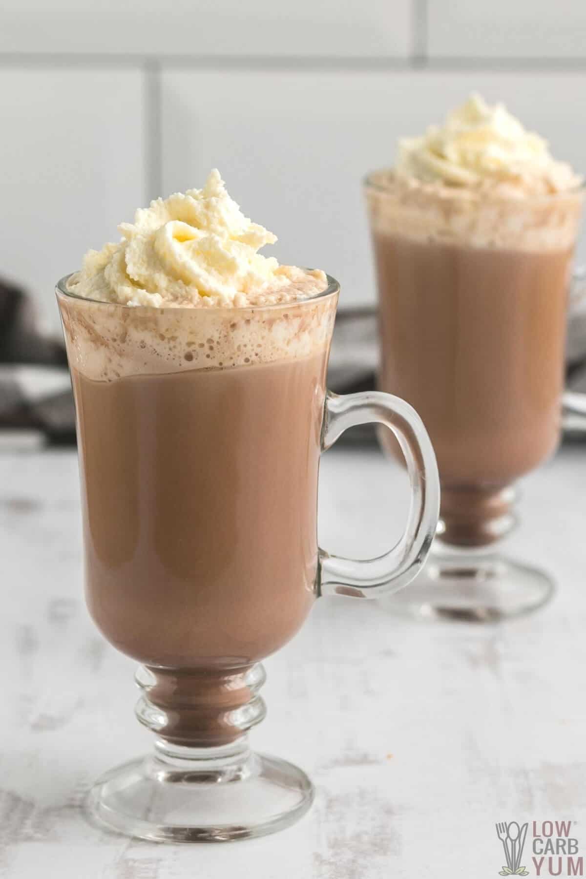 two glass cups of sugar free low carb keto hot chocolate topped with whipped cream