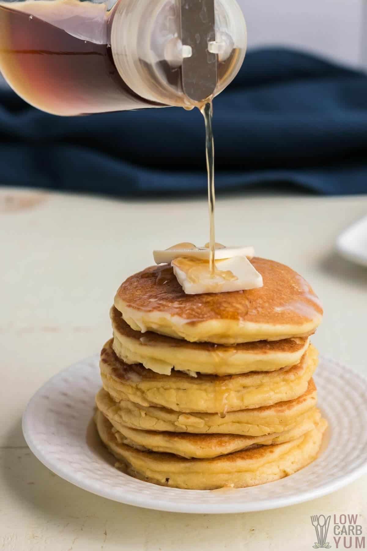 pouring syrup on oat fiber pancakes stack