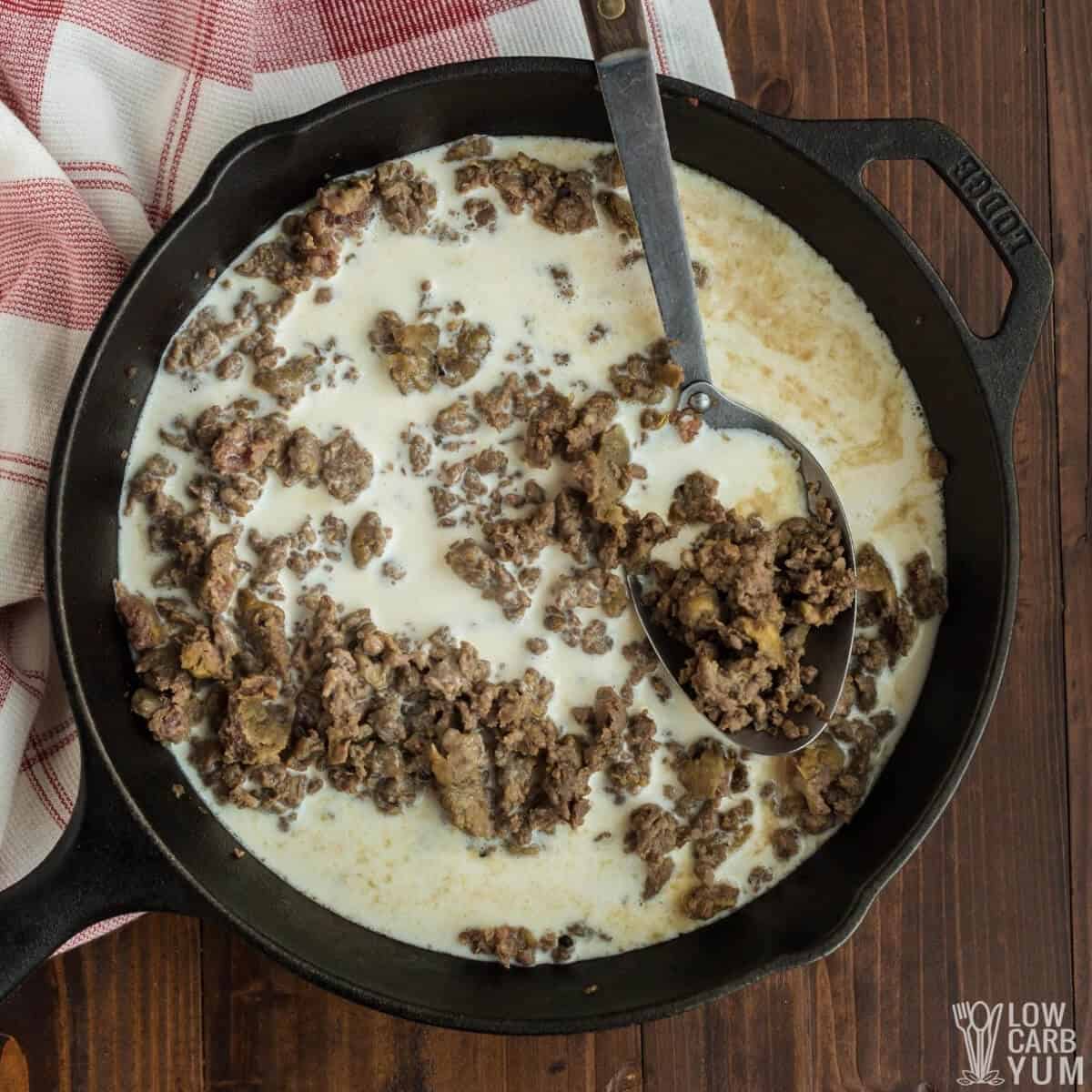 adding almond milk and cream to sausage in skillet