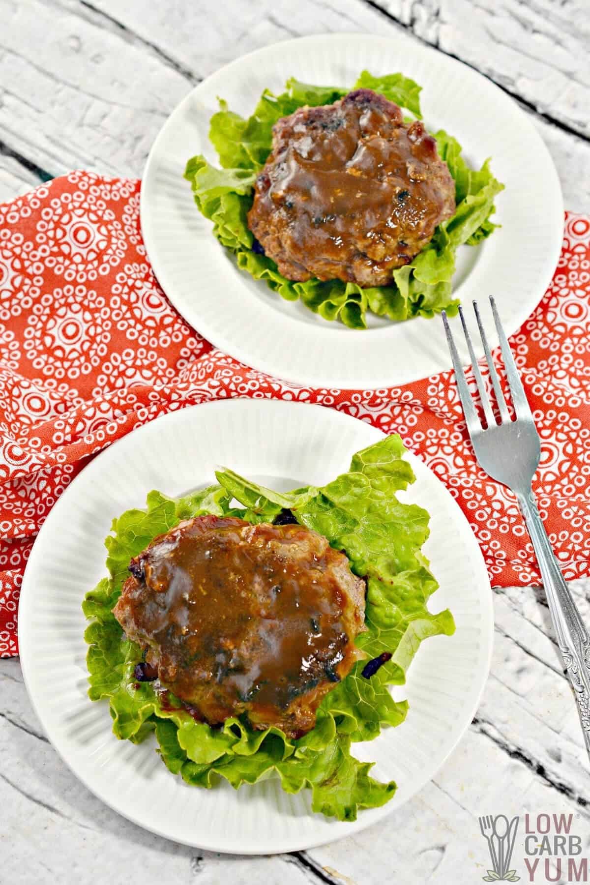 two hamburger steaks on lettuce served on a white plate