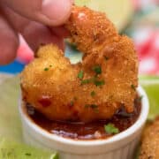 dipping keto coconut shrimp in sauce