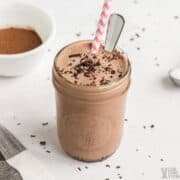 keto chocolate frosty recipe in small mason jar with straw and spoon