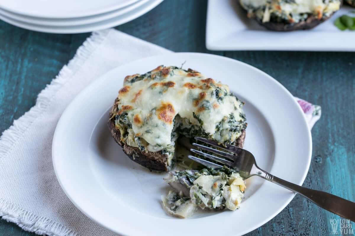 spinach stuffed portobello mushroom on plate with fork bite