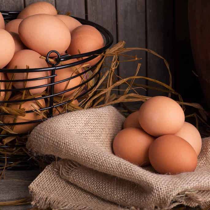brown eggs in basket and on linen.