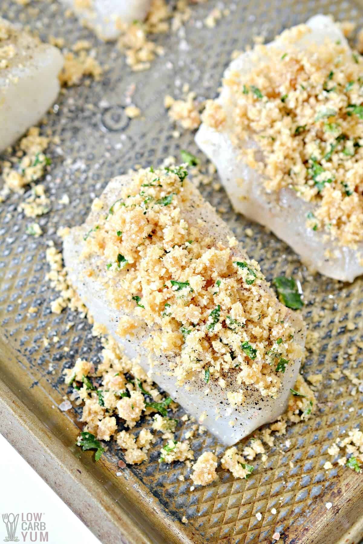 coated cod fillets on baking sheet with keto breadcrumbs