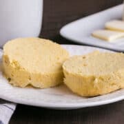 close up of muffin slices on white plate with mug and butter