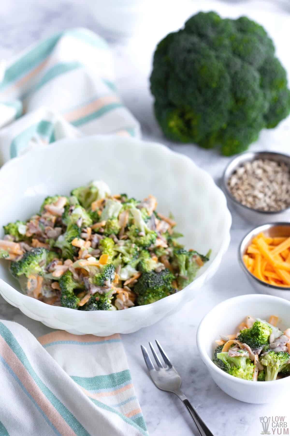 broccoli salad in white bowl with toppings on the side