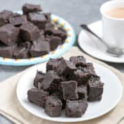 stacks of keto fudge on plates with coffee