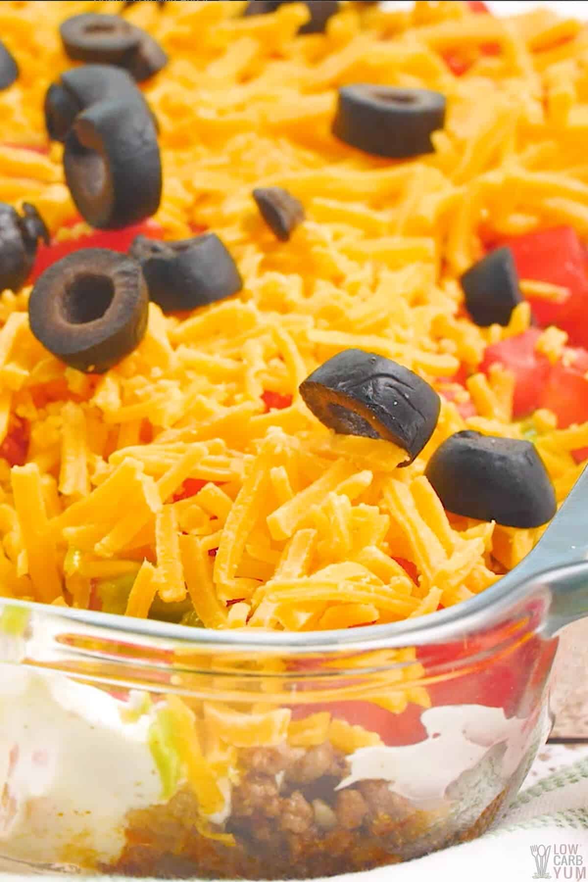 layered keto taco dip with meat in casserole pan