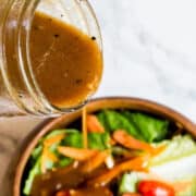 pouring balsamic vinaigrette dressing onto salad