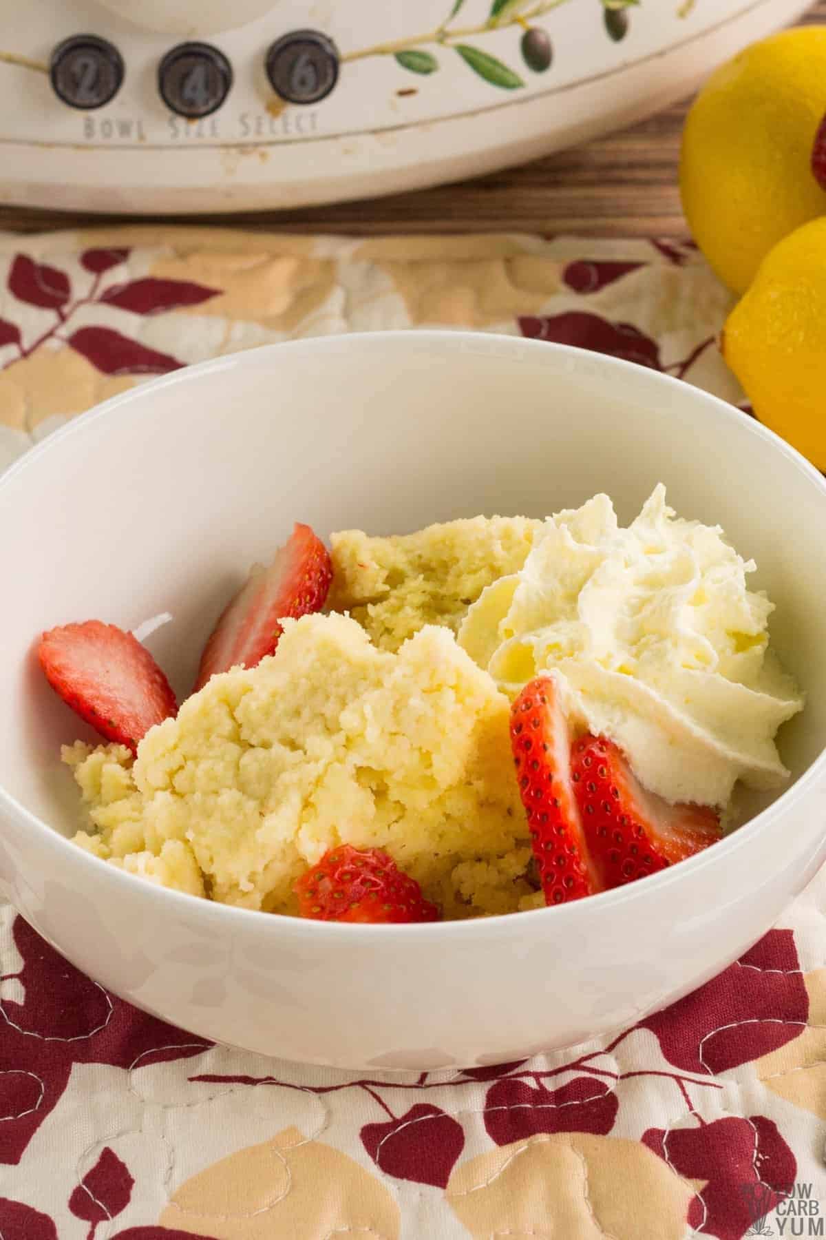 crock pot lemon cake in bowl with strawberries and whipped cream