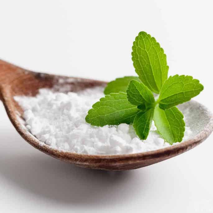 stevia powder on spoon with leaves