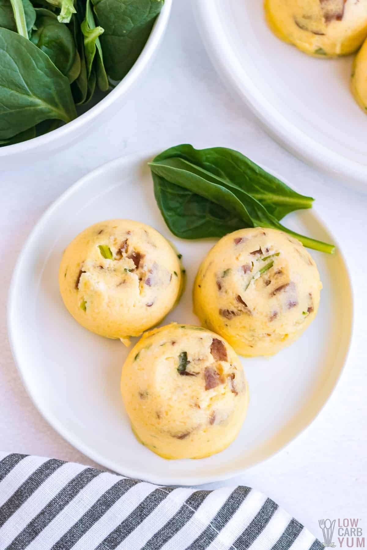 keto egg bites on white plates with baby spinach for proteins on keto diet