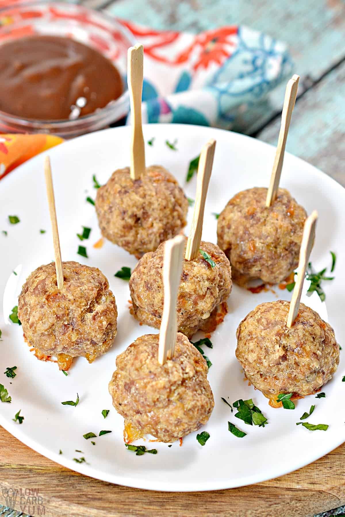 sausage balls with sticks on white plate with dipping sauce