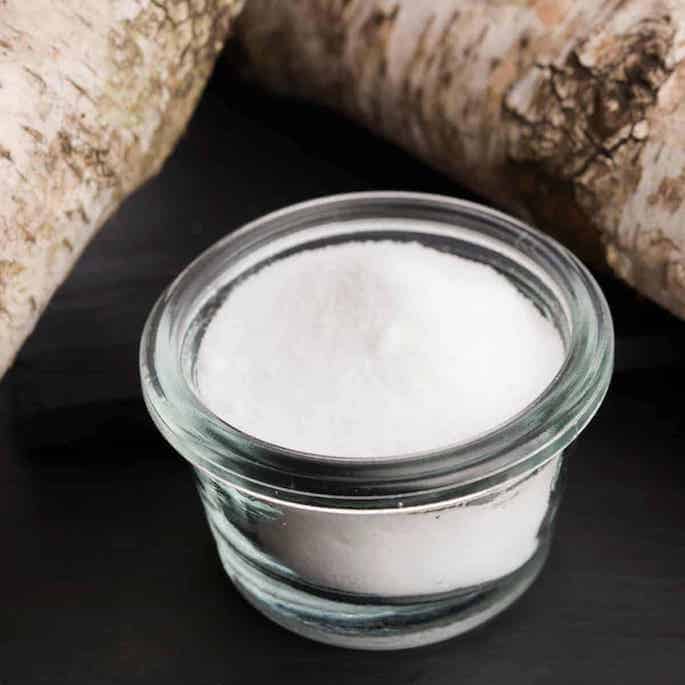 xylitol sweetener in glass cup with birch bark