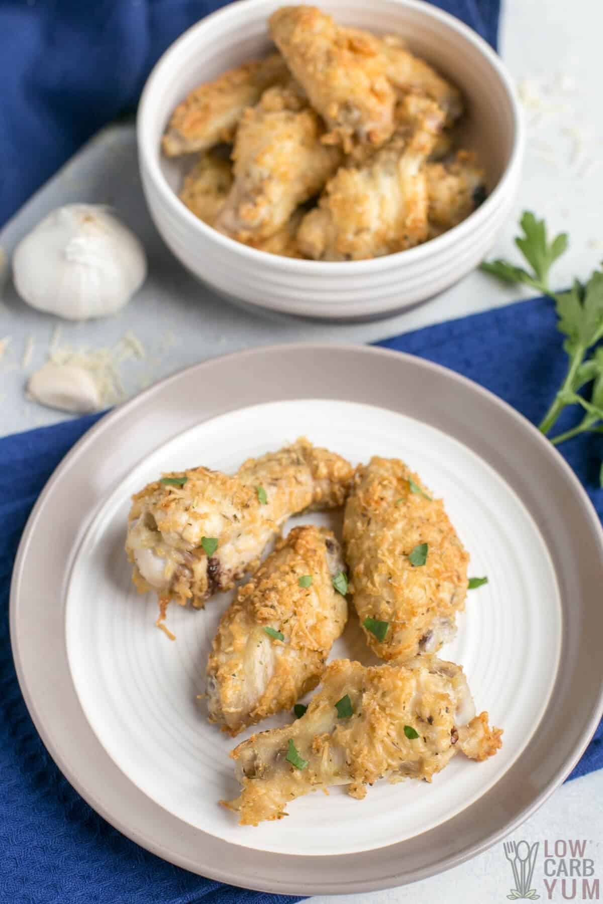garlic parmesan chicken wings in bowl and on plate