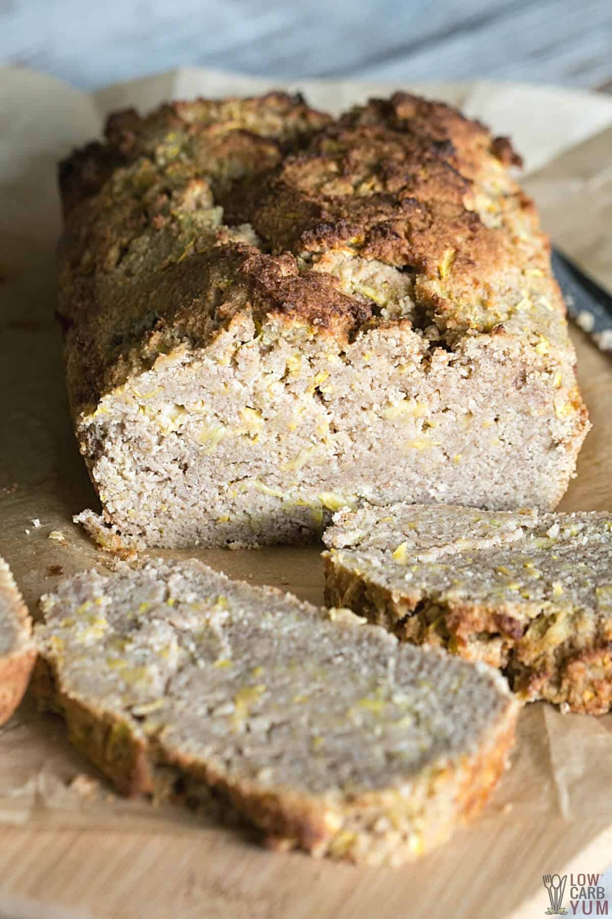 loaf of yellow squash bread sliced on wood cutting board