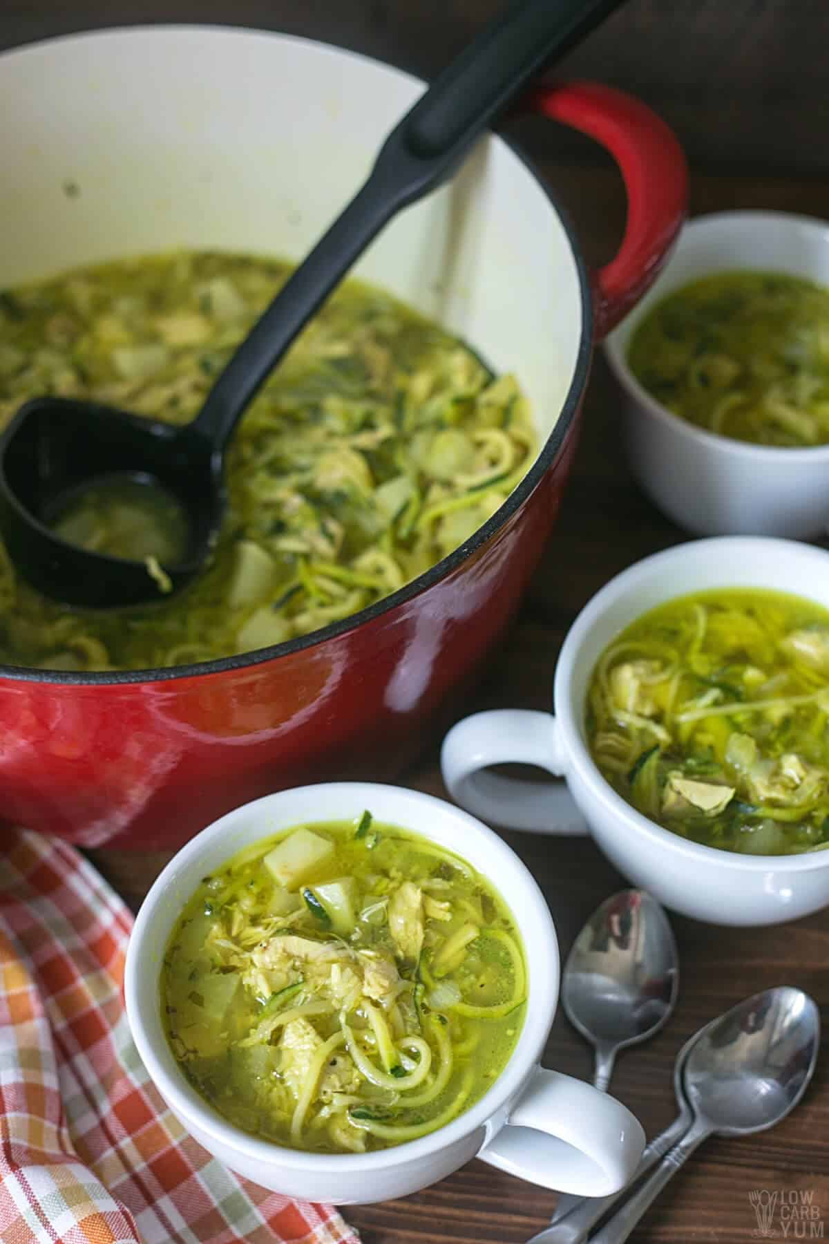 serving low carb chicken noodle soup in large white mugs