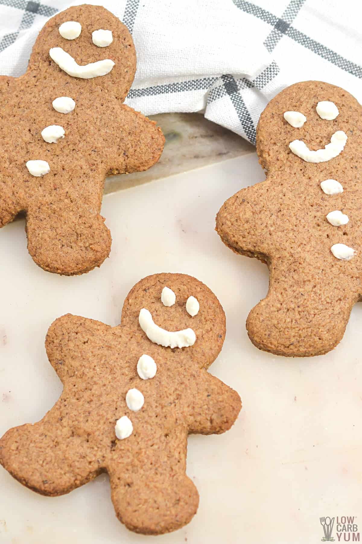 keto gingerbread cookies on white cutting board with plaid kitchen towel