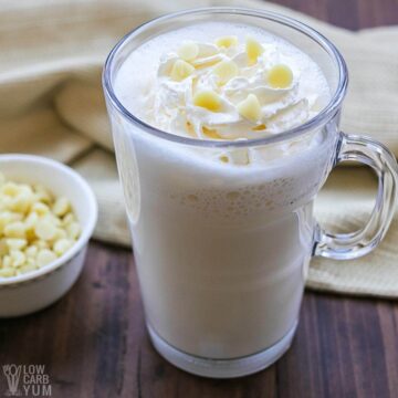 white hot chocolate in glass mug with chips and whipped cream