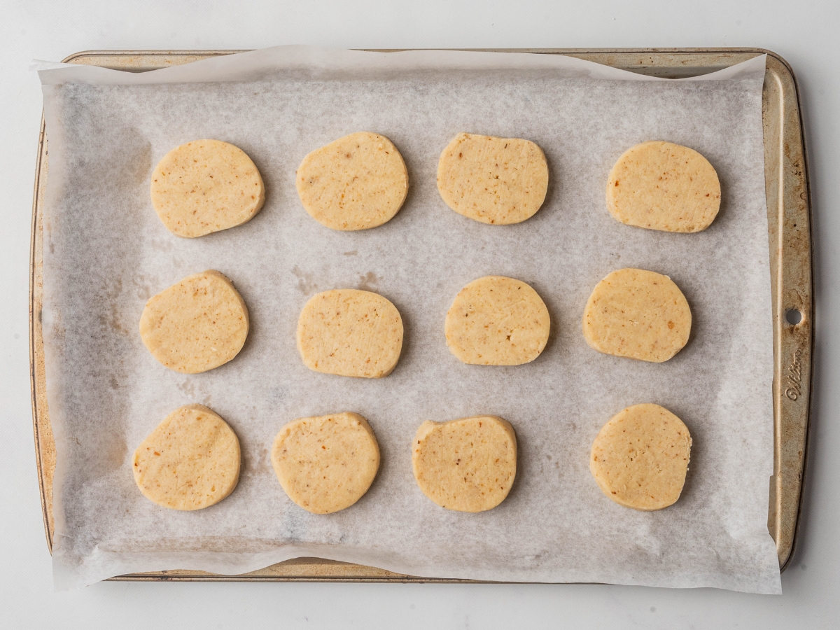 slicing cookie dough into round cookie shape onto a baking sheet