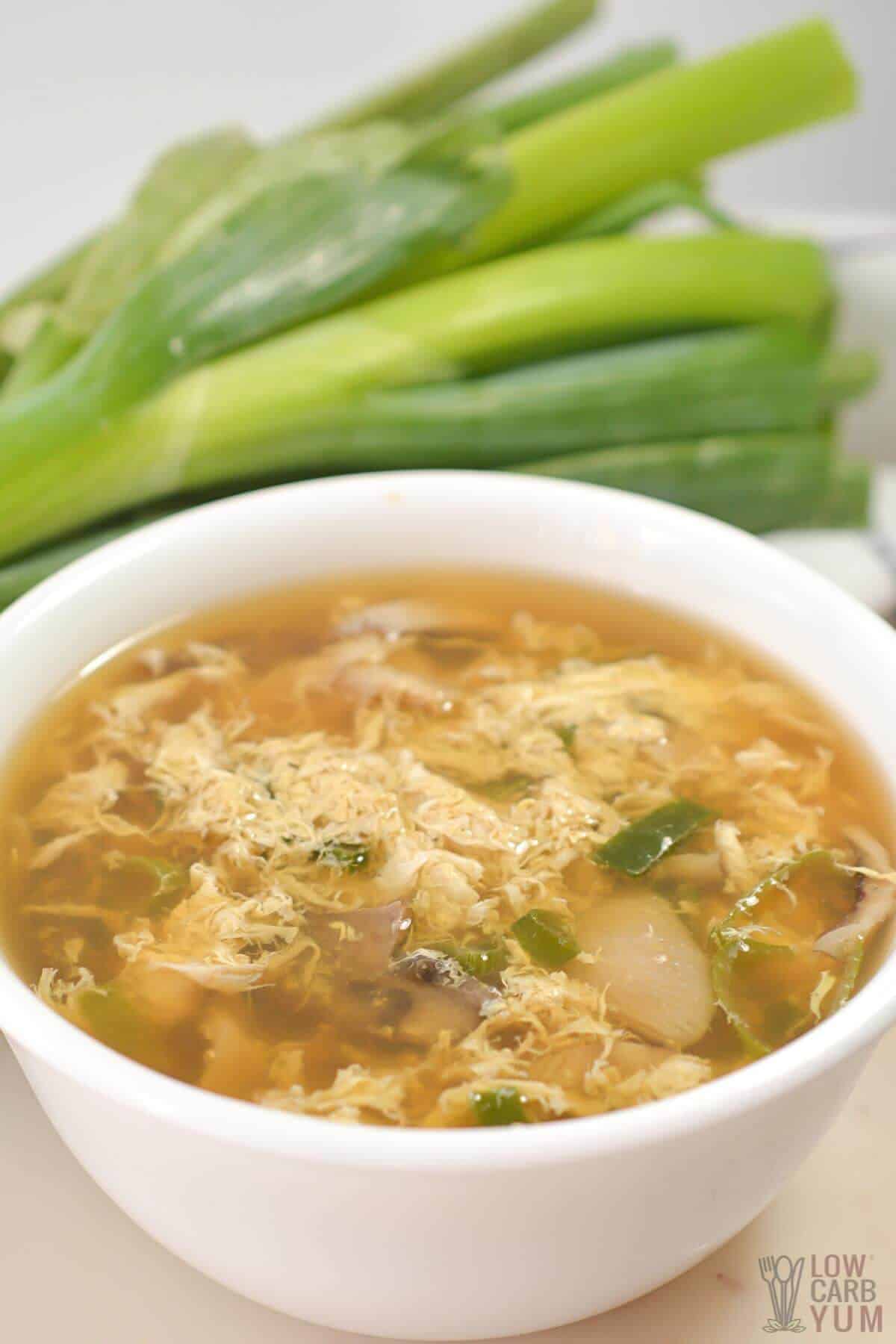 keto egg drop soup in white bowl with green onions
