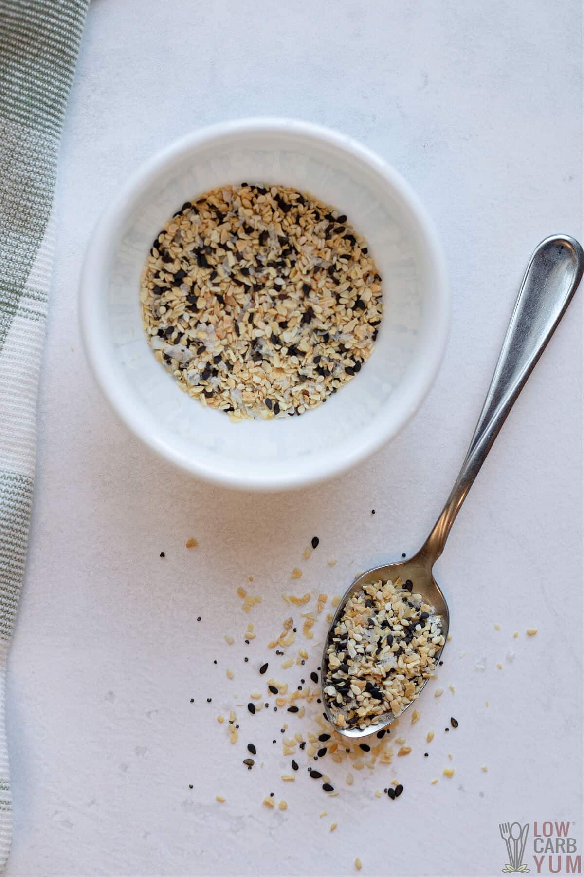 everything but the bagel seasoning in small white bowl and on silver spoon