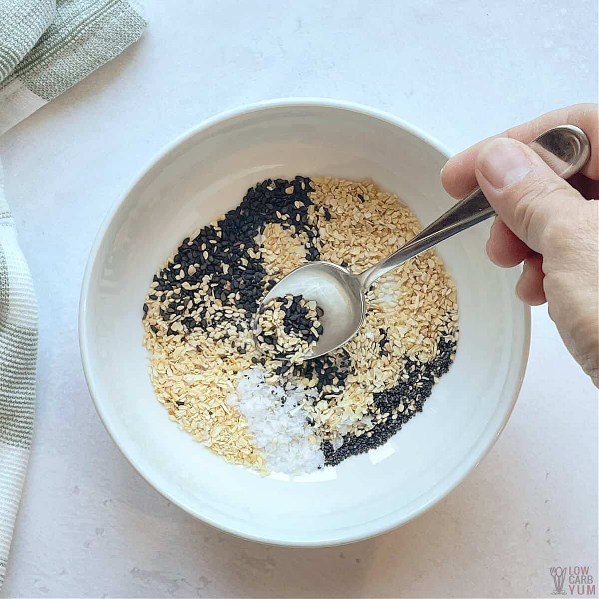 mixing bagel seasoning ingredients together in small white bowl