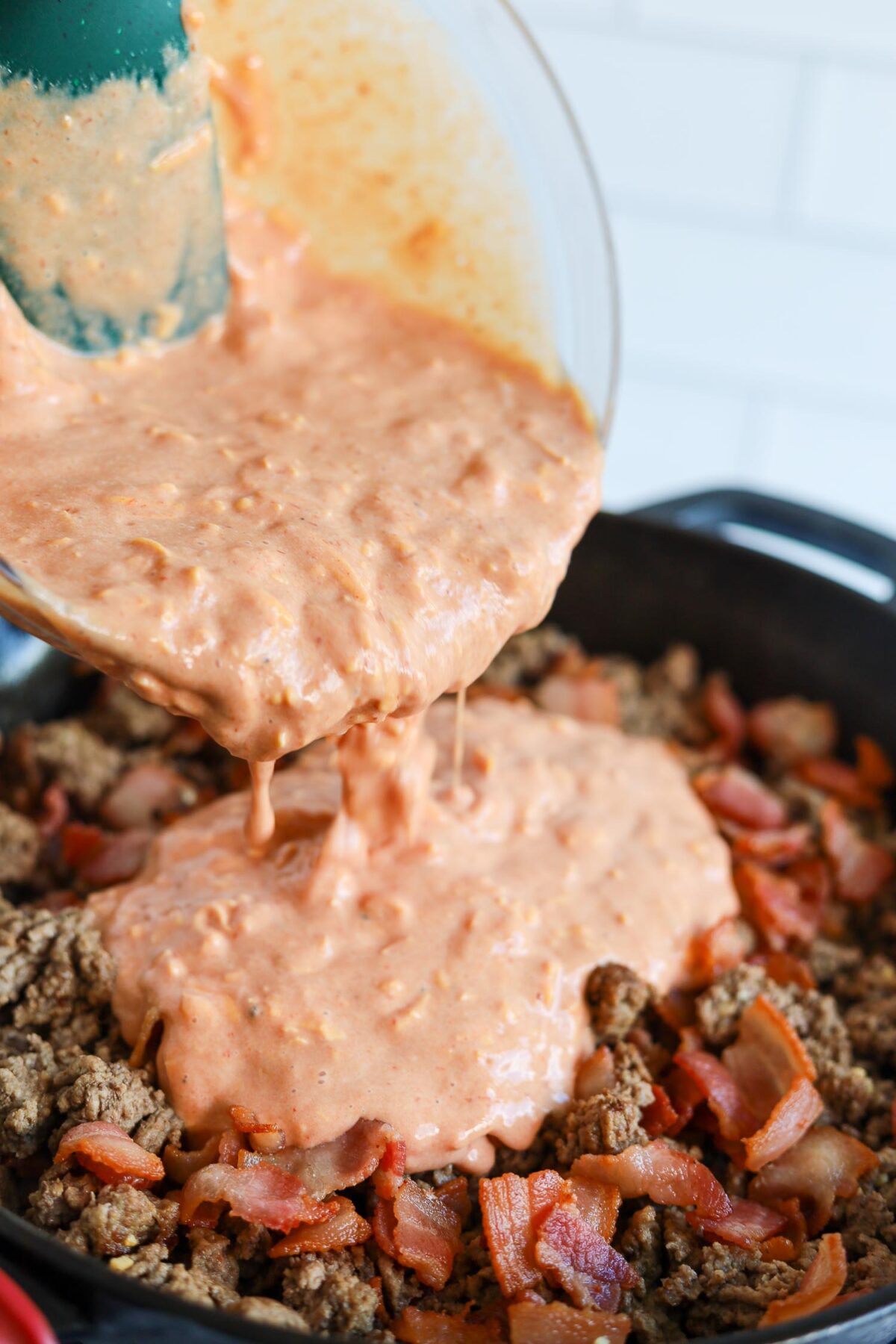 mixing cheesy egg mixture with ground beef in skillet