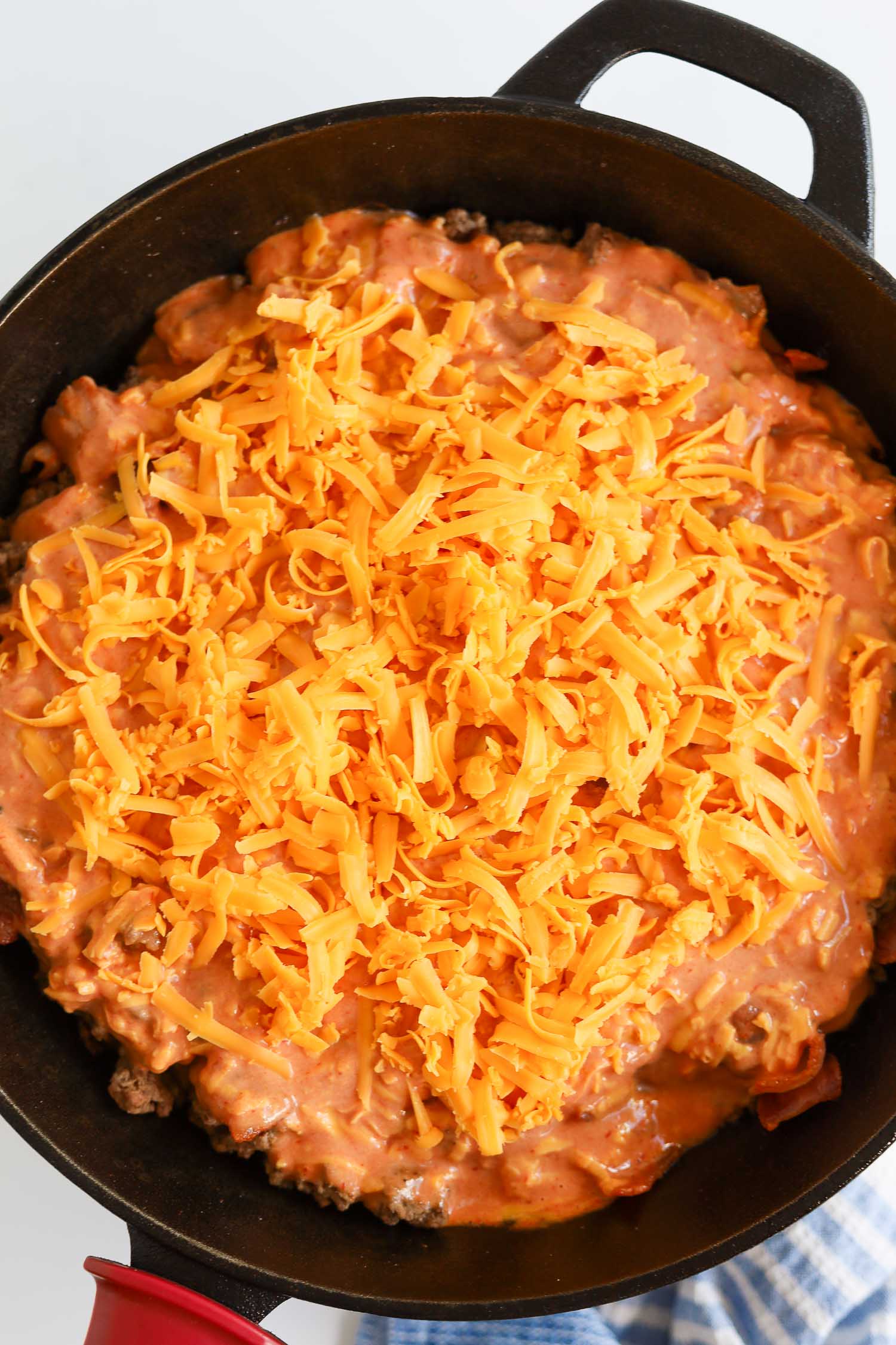 adding shredded cheese over the top of beef skillet